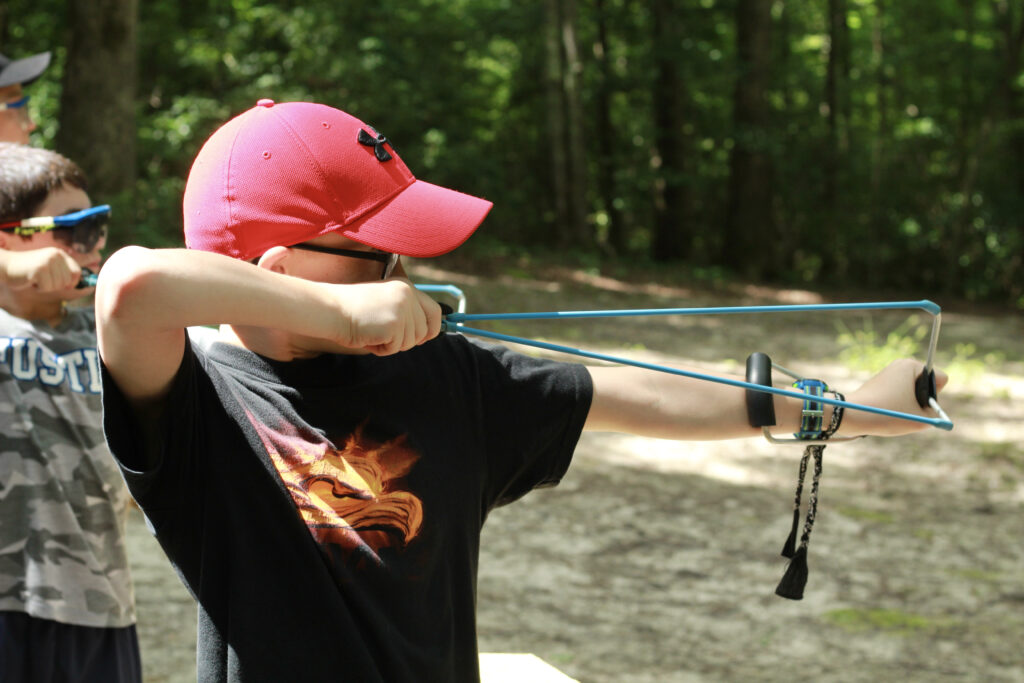 A Camper Aiming A Slingshot At A Target, One Of Many Group Activities At Wcrc.