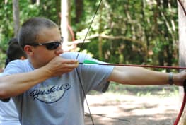 A Boy Shooting A Bow And Arrow At The Archery Range At Wcrc While On A Family Camping Trip