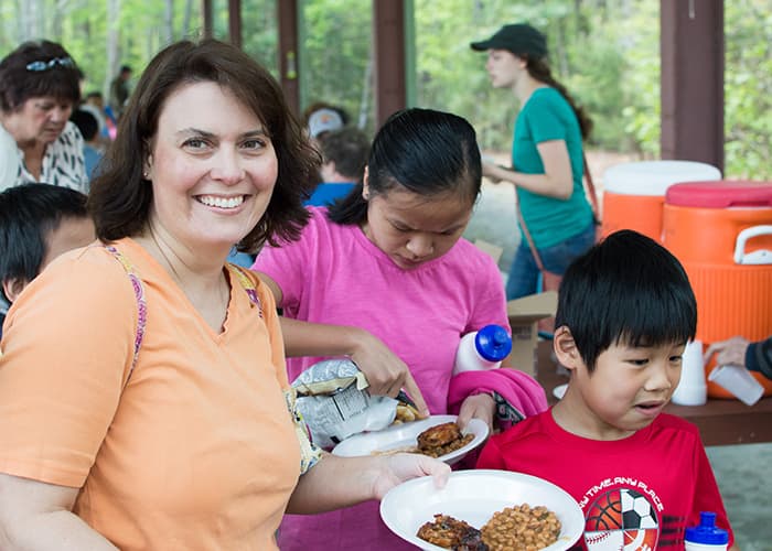 A Family Enjoying A Meal Outdoors During Family Camp At Wcrc In Williamsburg, Virginia