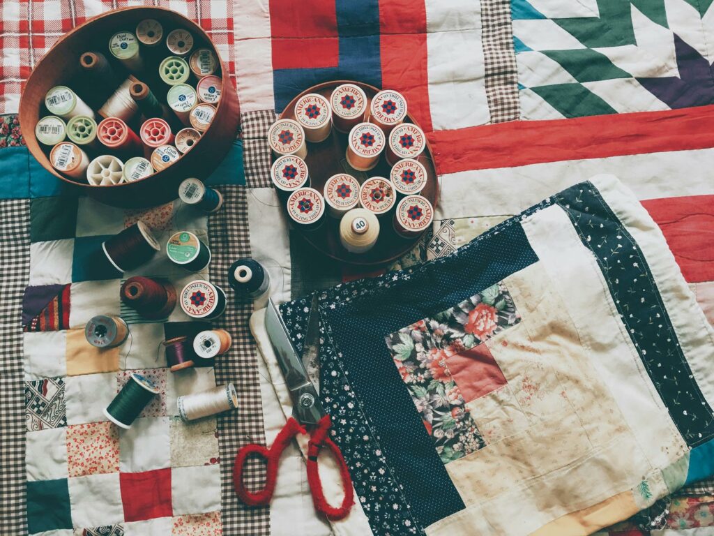Quilting Supplies resting on handmade quilts, representing the things attendees of the Quilting Retreat at WCRC can expect to work.