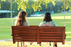 Serving Others Starts With A Respite: Why It’s Okay To Step Away 3 Two Women Sitting On A Swing Bench, Sharing Support And Connection During A Caregiver Retreat